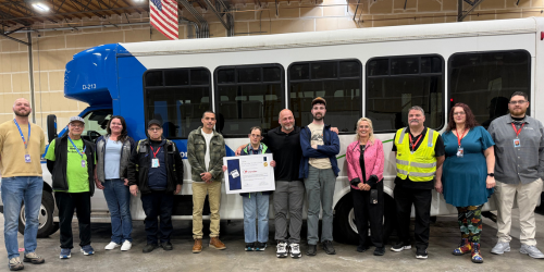 The Transdev Crew at the presentation of the Employer of the Month award. A line of people in front of a Community Transit bus.